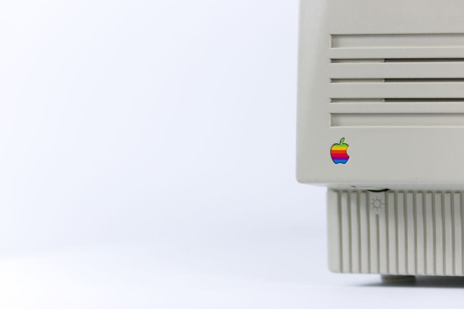 Close-up de un monitor de computadora vintage con un logo colorido sobre un fondo minimalista.