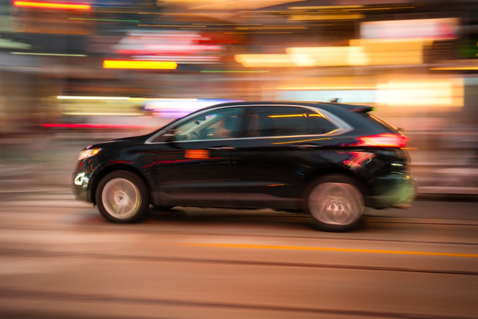 SUV negro en movimiento con fondo urbano, transmitiendo velocidad y vida de ciudad.