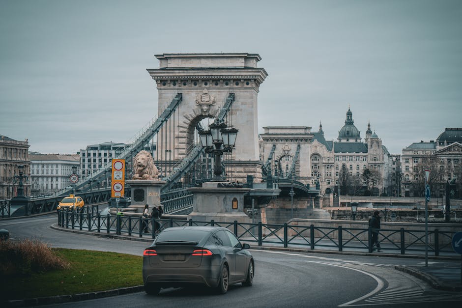 Vista del icónico Puente de las Cadenas en Budapest con un coche en primer plano en un día tranquilo.