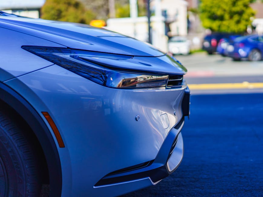 Vista detallada del faro y el parachoques de un elegante automóvil moderno capturados en un entorno urbano.