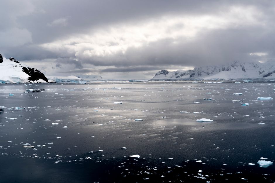 Una vista impresionante de los mares helados de la Antártida bajo nubes dramáticas, reflejando la serena atmósfera invernal.