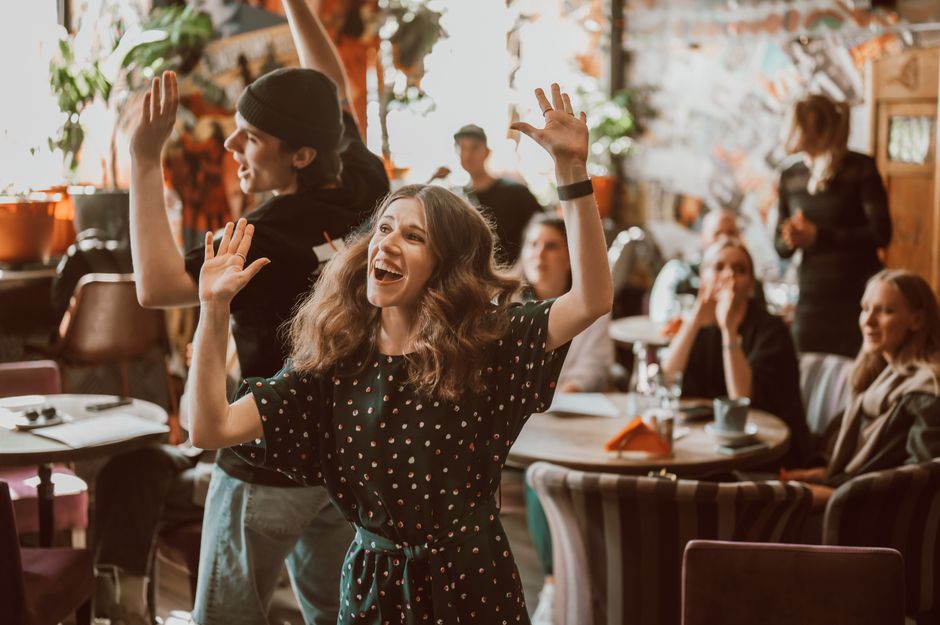 Una celebración animada en interiores con una joven pareja alegre bailando entre amigos.