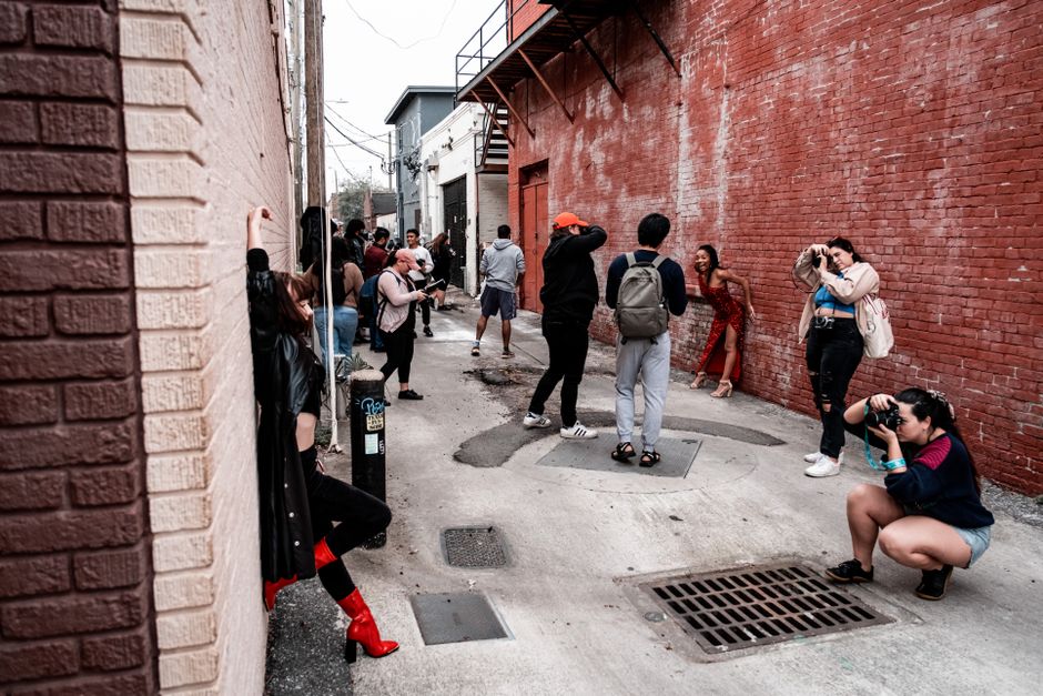 Una sesión de fotos animada con fotógrafos y modelos en un vibrante callejón urbano.