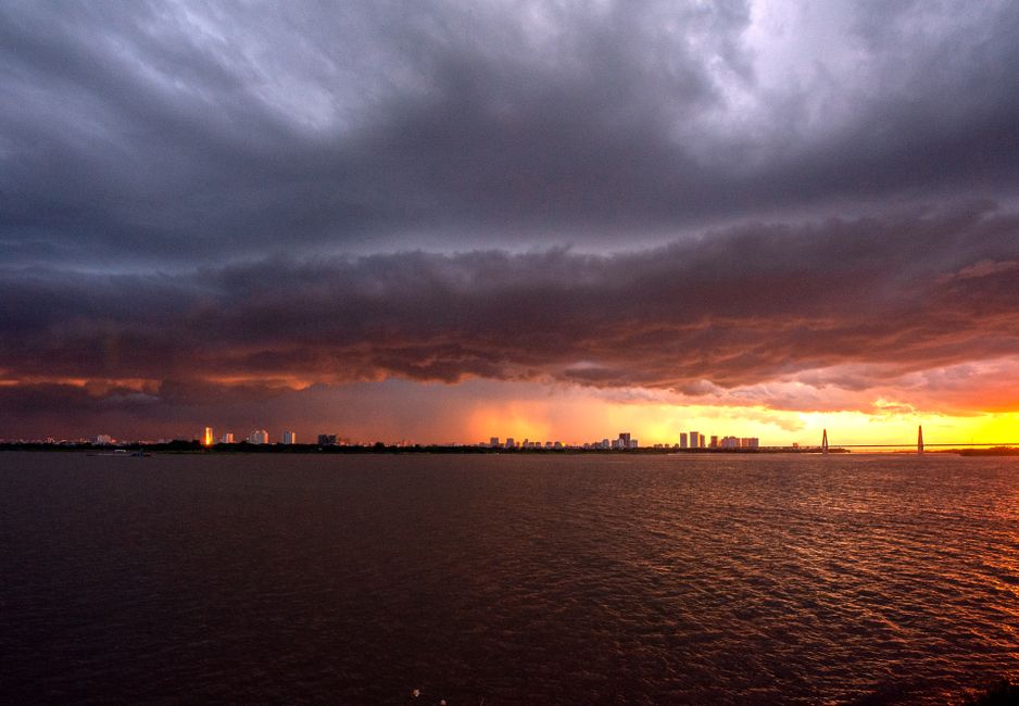 El perfil urbano de una ciudad bajo un cielo tormentoso y dramático, con una puesta de sol vibrante, ofrece un poderoso contraste.