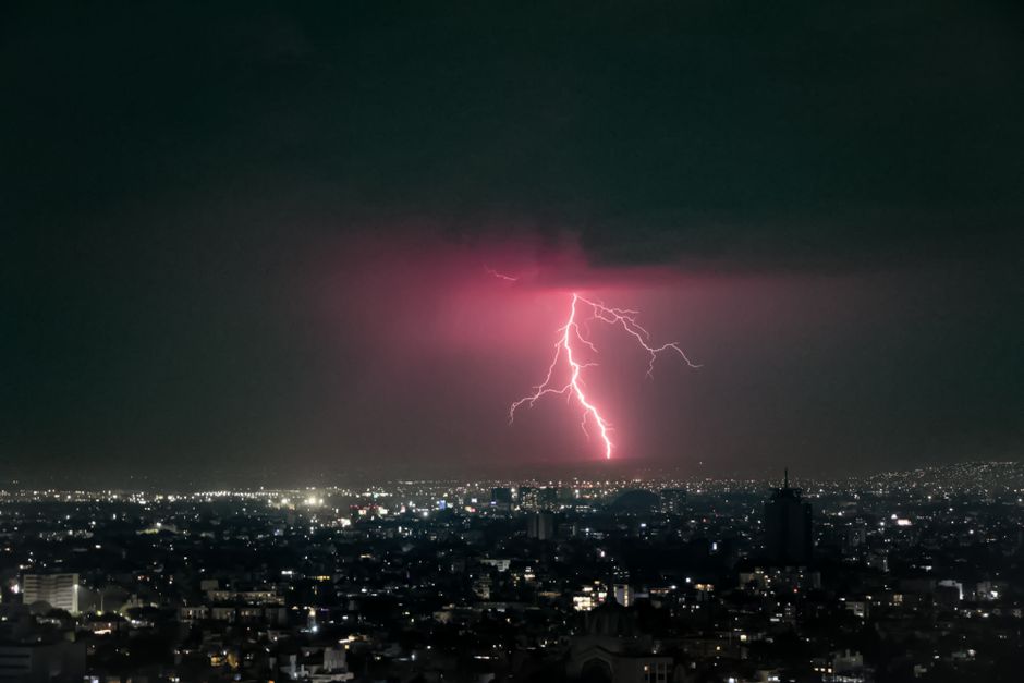 Cautivador paisaje urbano de la Ciudad de México con un rayo vívido iluminando el cielo nocturno.