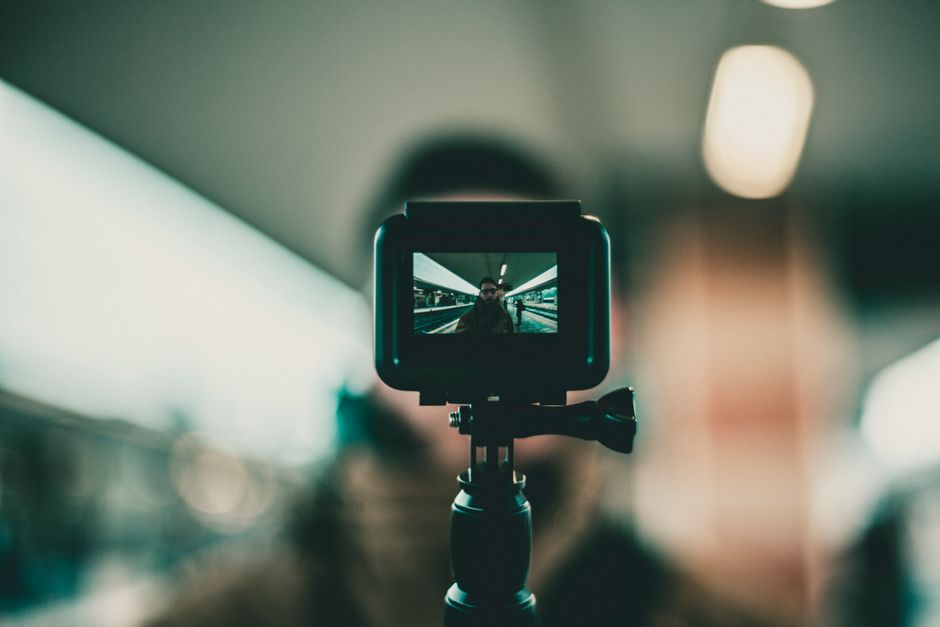 Una cámara de acción enfocada grabando a un vlogger en una estación de tren con fondo desenfocado.