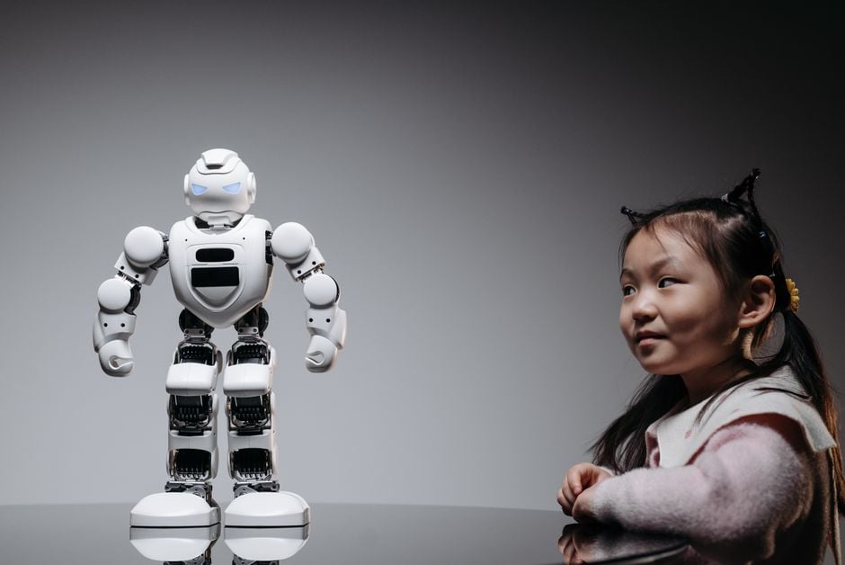 Una joven niña asiática interactúa con un robot de juguete de alta tecnología, mostrando innovación y curiosidad.