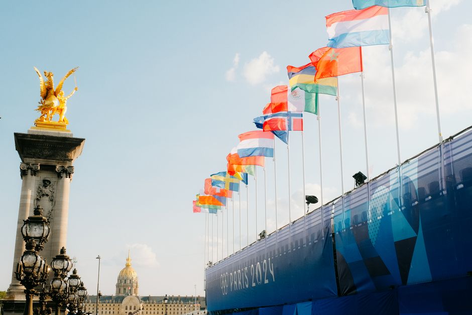 Banderas coloridas ondean con orgullo en el Puente Alejandro III para París 2024, capturando un ambiente festivo.
