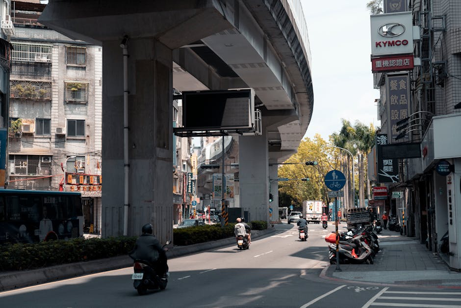Una calle bulliciosa bajo un paso elevado de la autopista en la ciudad de Nuevo Taipéi, Taiwán, con motocicletas y ambiente urbano.