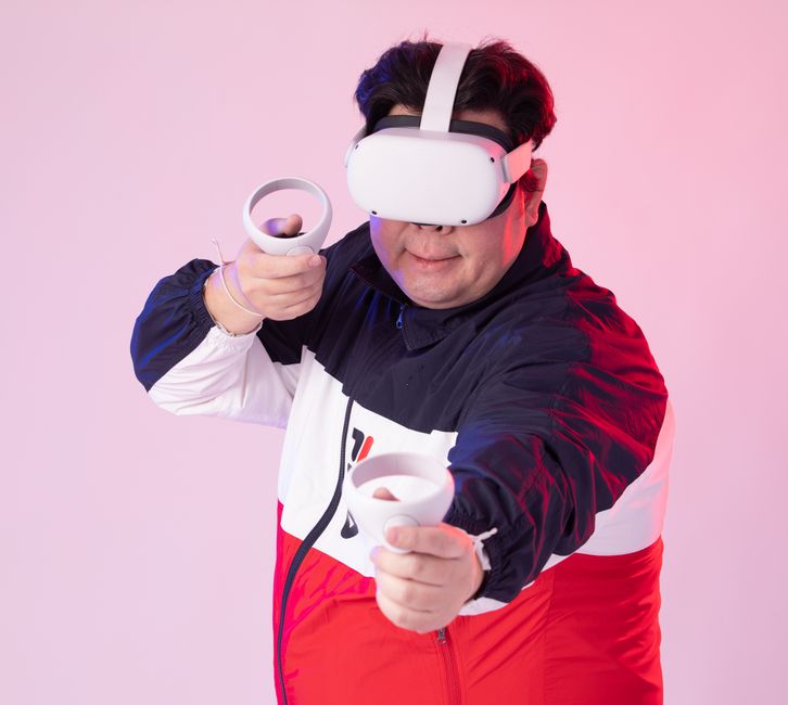 Un hombre sumergido en un juego de realidad virtual, usando auriculares VR y controles, toma de estudio.