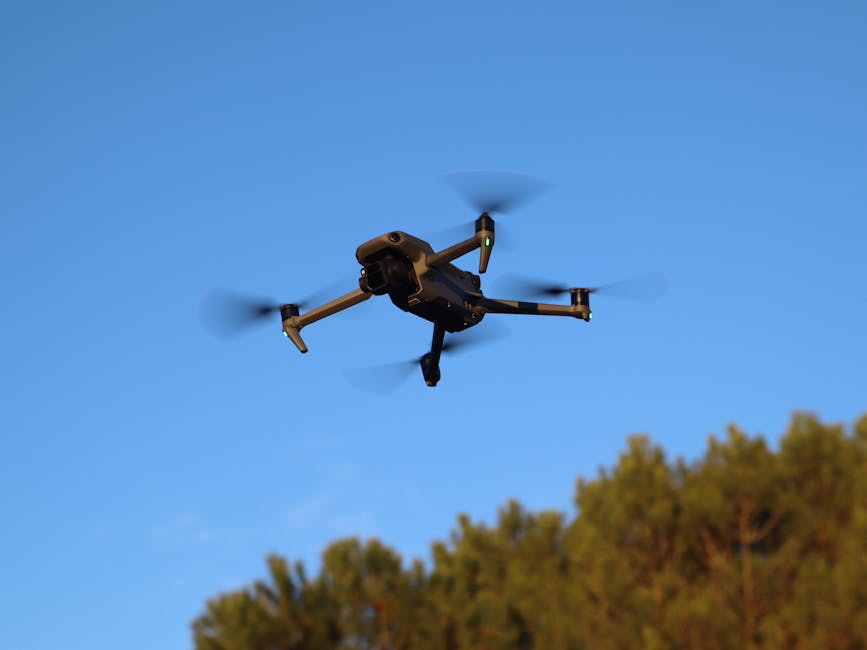 Un dron flotando al aire libre a la luz del día con hélices borrosas por el movimiento contra un cielo azul en Valladolid, España.