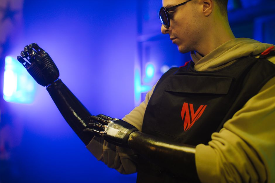 Un hombre examina su brazo protésico avanzado en un entorno futurista iluminado con neón.