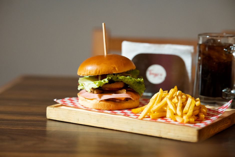 Deliciosa hamburguesa gourmet con patatas fritas y bebida en una bandeja de madera. Perfecta para los amantes de la comida rápida.