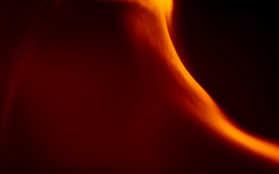 Arte abstracto dinámico con un patrón de luz naranja similar a una llama contra un fondo oscuro.