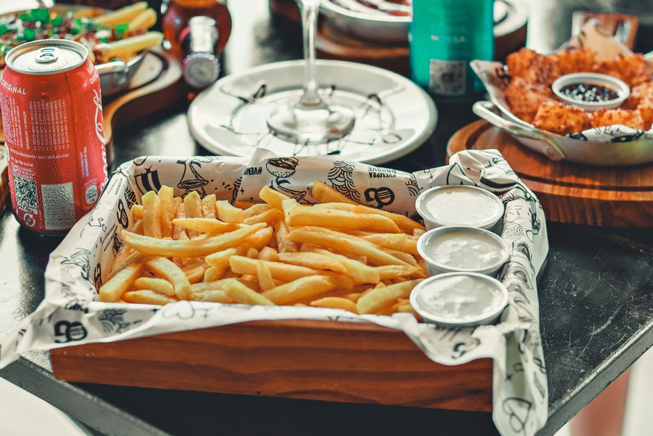 Una tentadora bandeja de papas fritas con salsas servidas en una bandeja de madera, ideal para reseñas de comida.