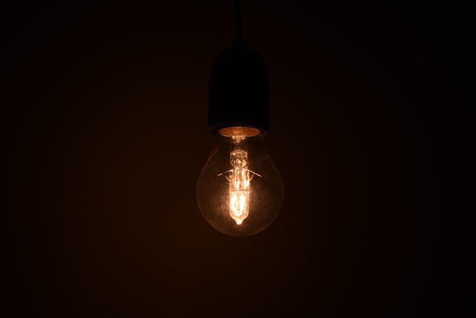 Vista en primer plano de una bombilla iluminada brillando en un entorno oscuro, emitiendo luz cálida.