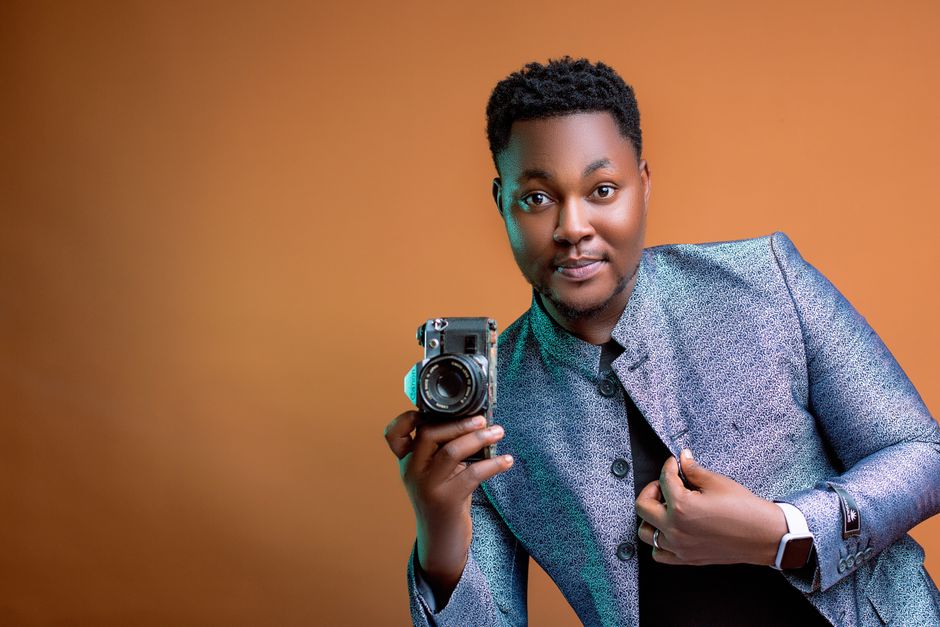 Retrato de estudio de un fotógrafo seguro sosteniendo una cámara vintage con un atuendo elegante.