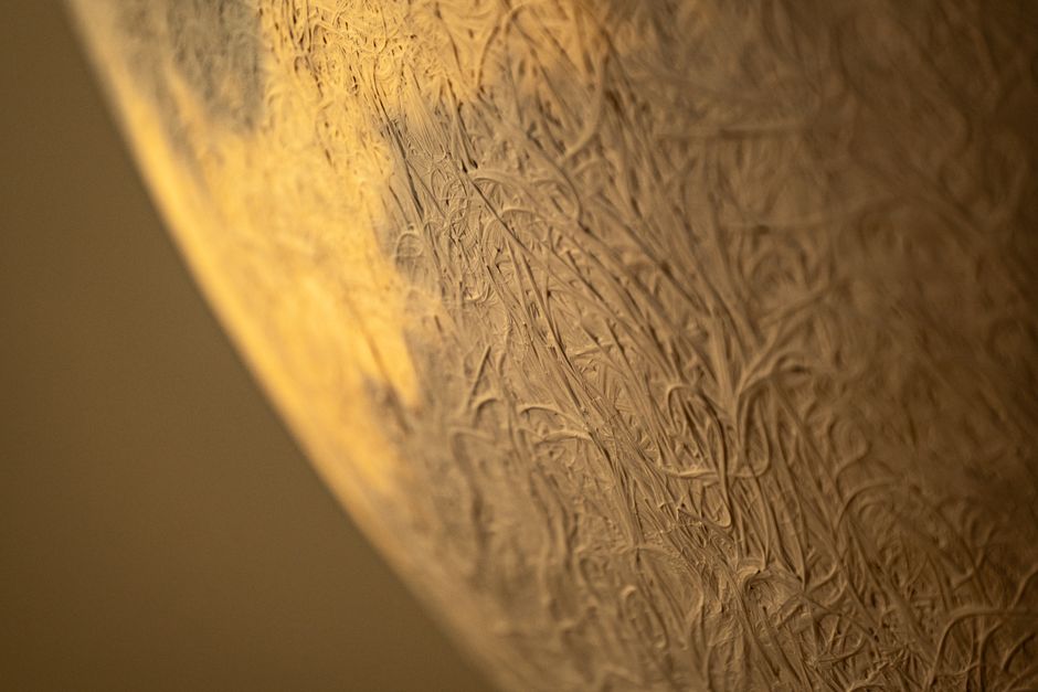 Acercamiento detallado de una superficie texturizada con luz cálida que proyecta sombras, creando un efecto abstracto artístico.