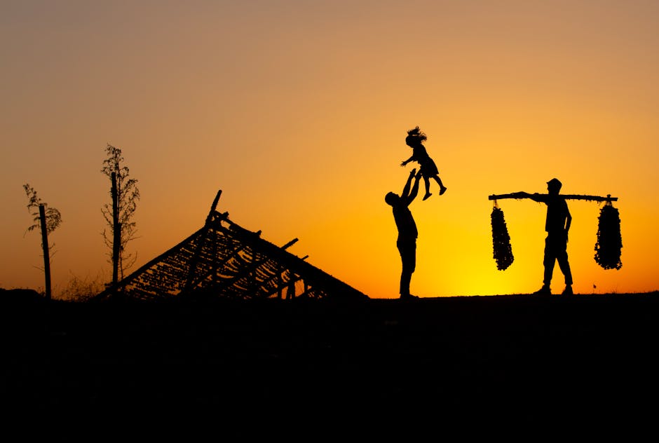 Silueta de una familia disfrutando de una puesta de sol, con un vibrante cielo naranja de fondo.