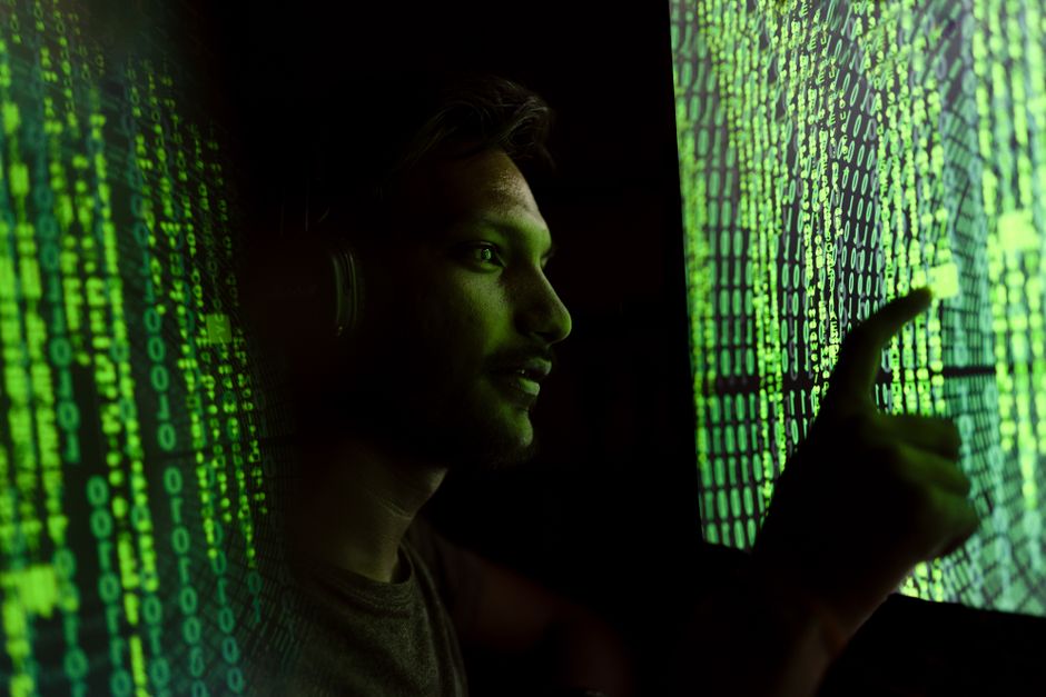 Una persona interactúa con código digital en una pantalla, simbolizando tecnología de ciberseguridad.