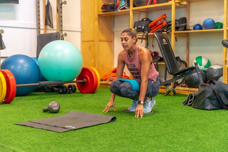 Mujer en forma con ropa de deporte agachada durante el entrenamiento en un gimnasio en Orlando.