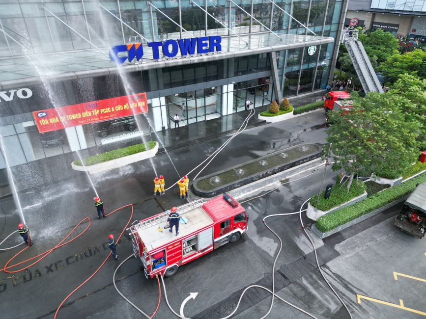 Simulacro de seguridad contra incendios en la CM Tower con bomberos y camión en acción.