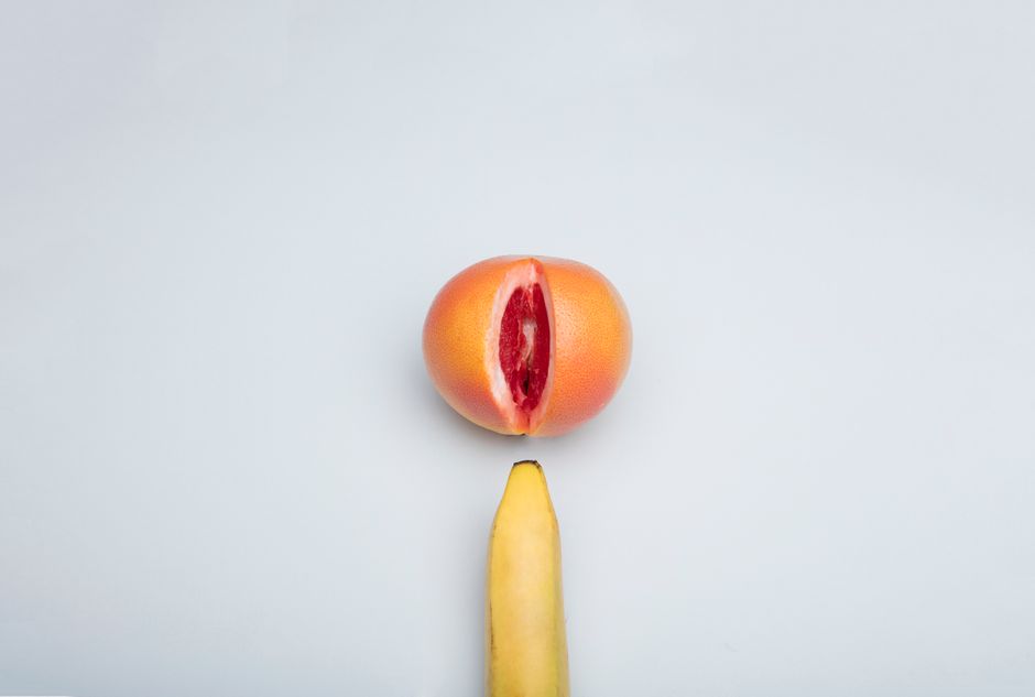 Disposición conceptual de frutas con un plátano y una toronja sobre un fondo blanco.