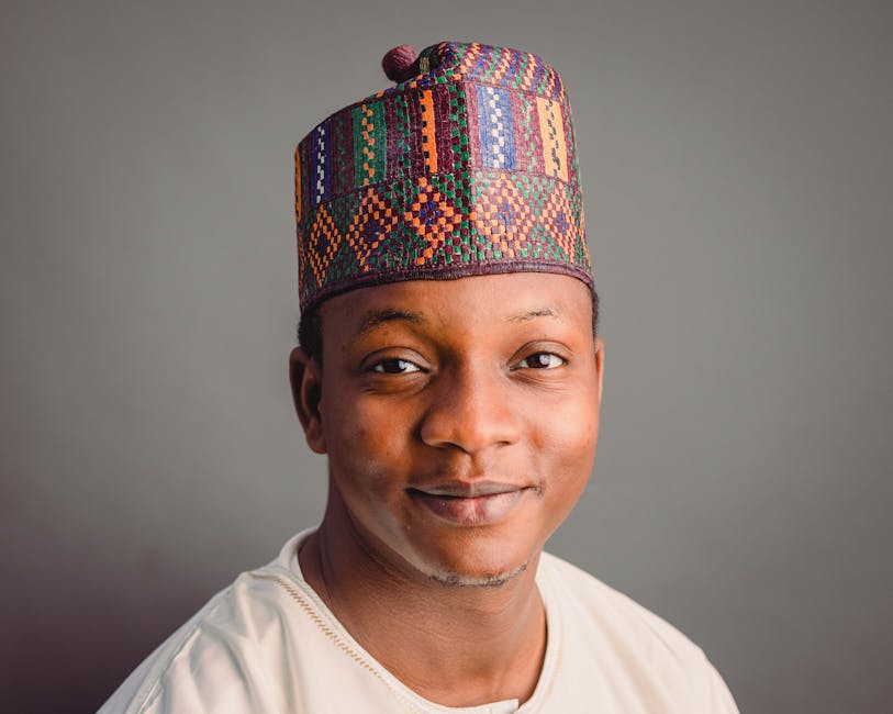 Retrato de un hombre nigeriano sonriente que lleva un sombrero tradicional colorido.