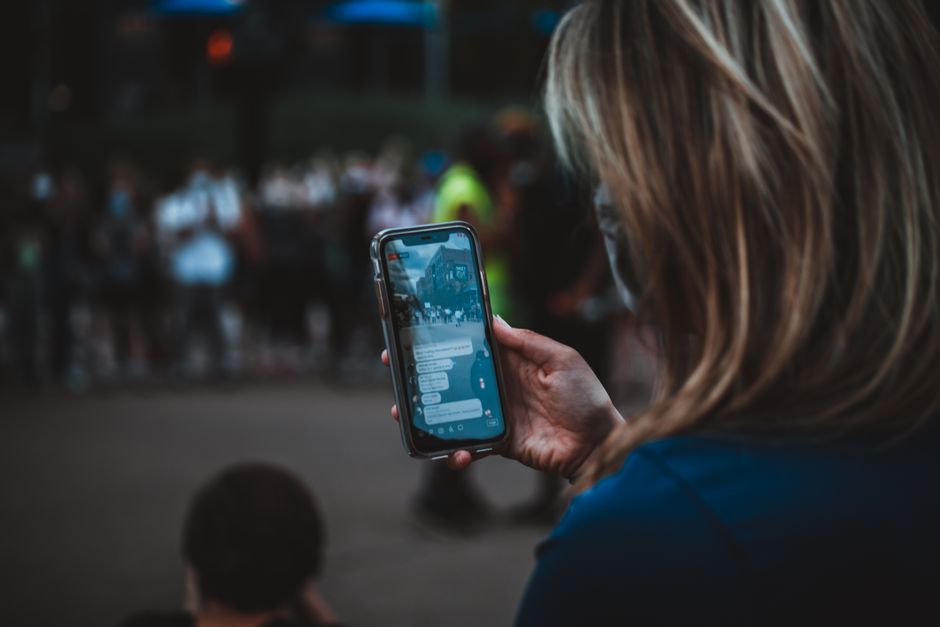 Una mujer usando un smartphone durante una protesta en una calle de la ciudad.