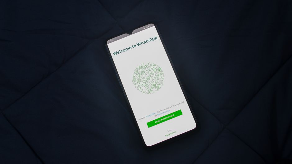Smartphone mostrando la pantalla de inicio de sesión de WhatsApp sobre una superficie oscura. Vista aérea.