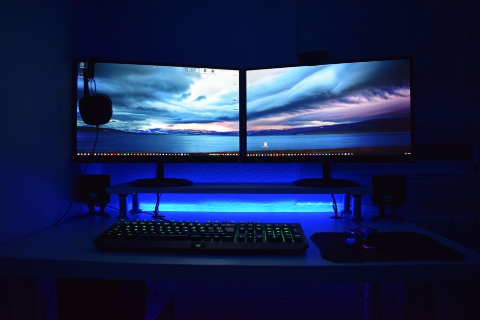 Monitores duales con luz azul en una configuración de escritorio para juegos.