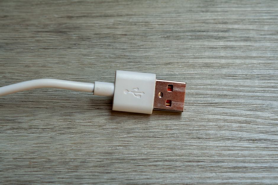 Un close-up detallado de un conector USB blanco colocado sobre una superficie de madera.