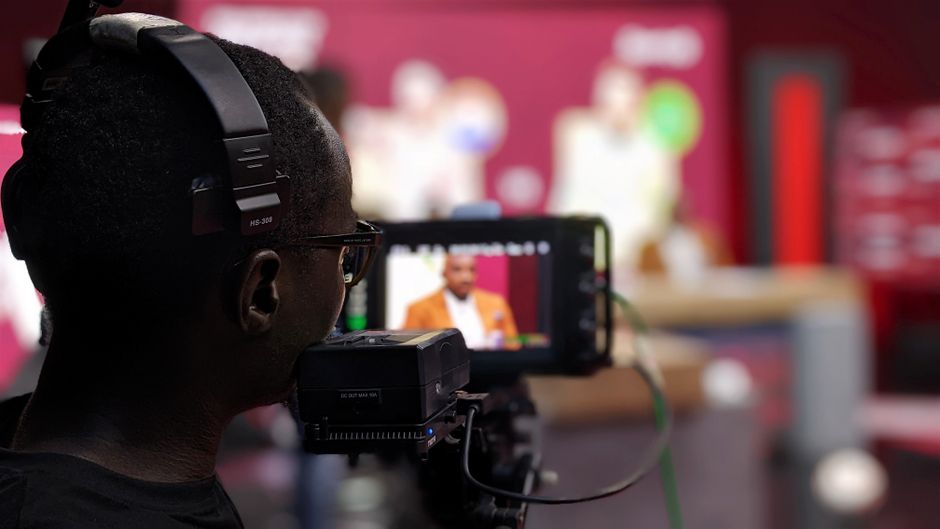 Primer plano de un camarógrafo con auriculares filmando un programa en un estudio.