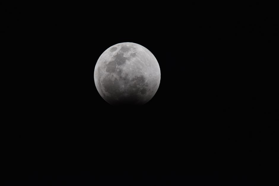 Foto detallada de un eclipse lunar que muestra las texturas de la superficie de la luna contra un cielo oscuro.